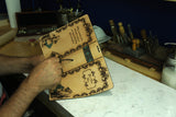 hands working on alice in wonderland leather journal cover